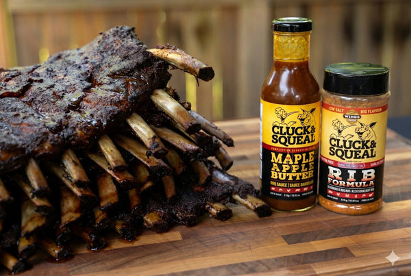 Juicy smoked ribs with Cluck & Squeal Maple Apple Butter BBQ sauce and Rib Formula seasoning on wooden board