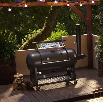 Black Cardinal smoker on wooden deck with string lights, surrounded by greenery and firewood.