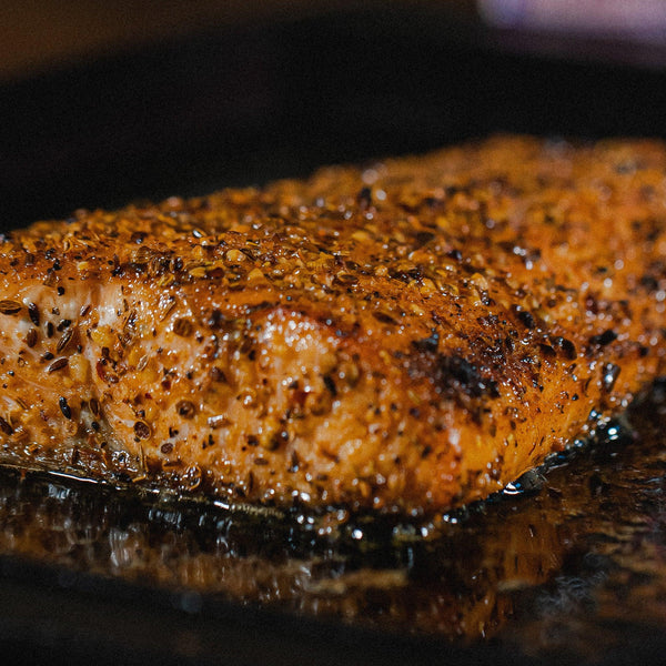 Juicy seasoned chicken breast sizzling on grill with herbs and spices