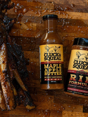 Cluck & Squeal Maple Apple Butter BBQ sauce and Rib Formula seasoning with glazed ribs on wood